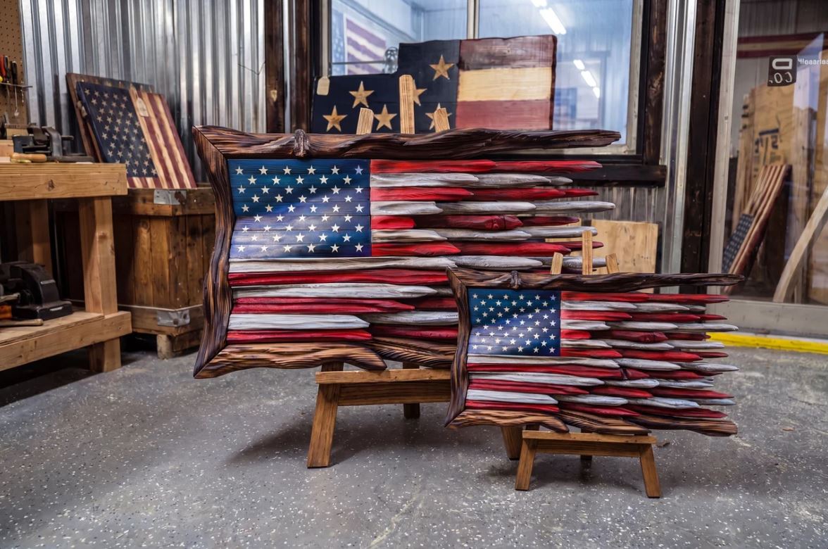Hank, the face of Hank's Flags, with carved wooden American flags in his workshop
